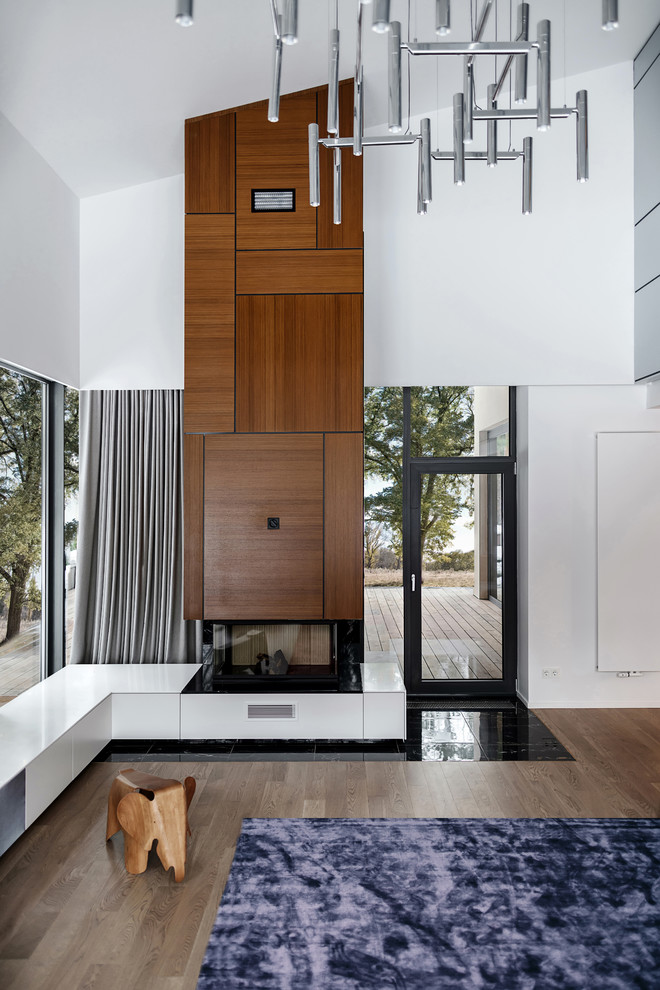 Mittelgroßes, Offenes Wohnzimmer mit weißer Wandfarbe, braunem Holzboden, Kamin, Kaminumrandung aus Holz und buntem Boden in Los Angeles