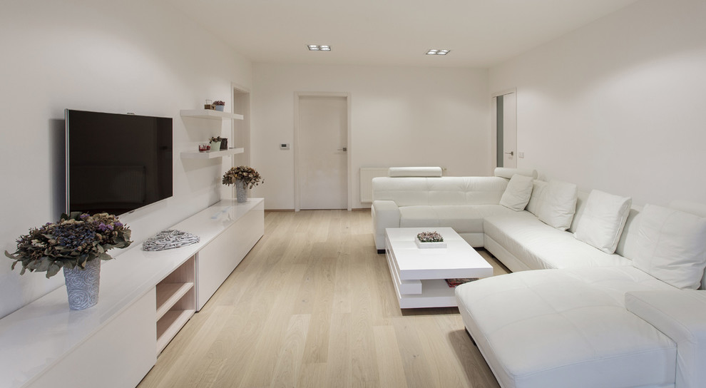 Ispirazione per un grande soggiorno minimalista aperto con sala formale, pareti bianche, parquet chiaro, nessun camino e TV a parete