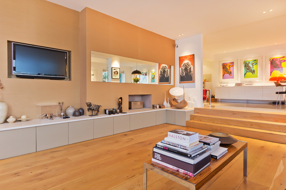 Foto di un soggiorno minimal aperto con pareti beige, pavimento in legno massello medio e TV a parete
