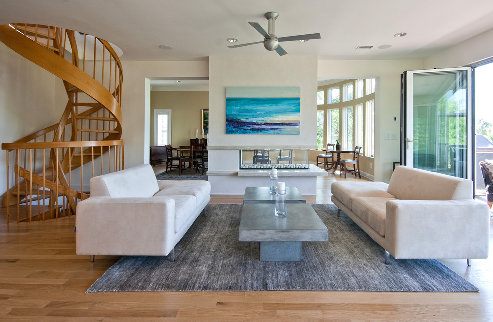 Example of an island style living room design in Charleston with white walls and a two-sided fireplace
