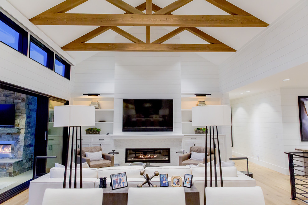 Landhaus Wohnzimmer mit weißer Wandfarbe, hellem Holzboden, Gaskamin, Kaminumrandung aus Holz, TV-Wand und beigem Boden in Seattle