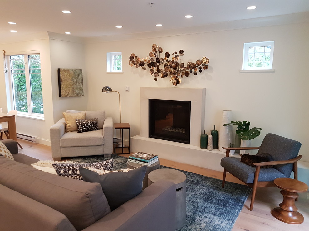 Photo of a small modern open plan living room in Vancouver with white walls, light hardwood flooring, a standard fireplace, a wooden fireplace surround and a wall mounted tv.