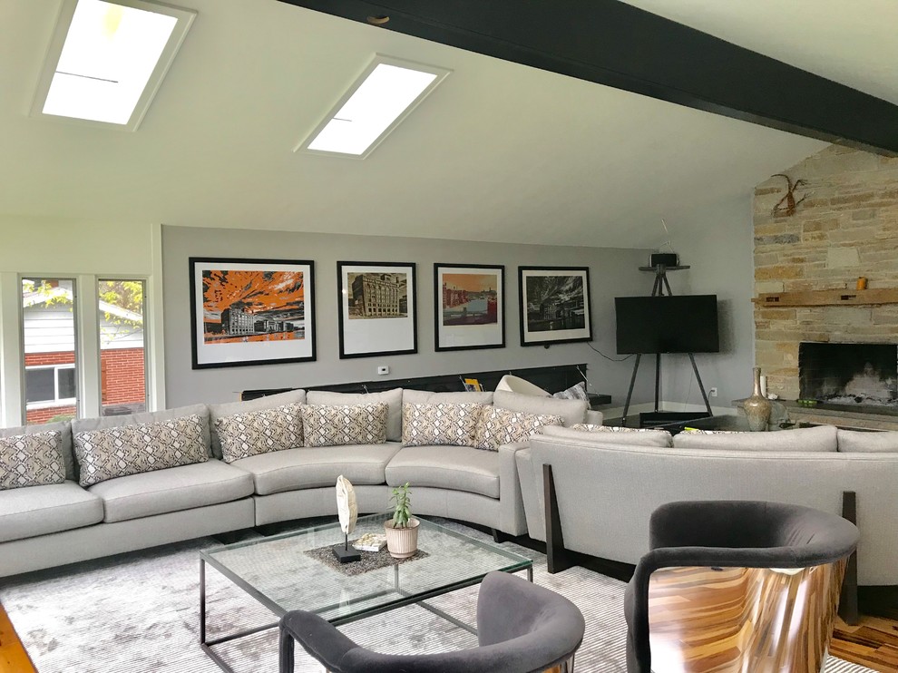 Стильный дизайн: большая открытая гостиная комната в стиле модернизм с серыми стенами, паркетным полом среднего тона, стандартным камином, фасадом камина из камня, отдельно стоящим телевизором и коричневым полом - последний тренд