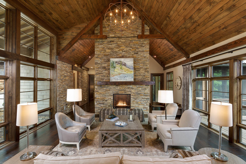 Large rustic open plan living room in Other with beige walls, dark hardwood flooring, a two-sided fireplace, a stone fireplace surround and feature lighting.