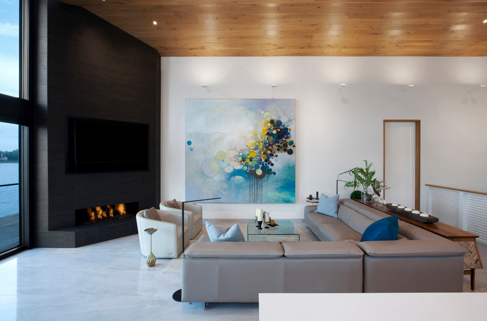 Идея дизайна: открытая гостиная комната среднего размера в стиле модернизм с белыми стенами, полом из керамогранита, угловым камином, фасадом камина из плитки, телевизором на стене и серым полом