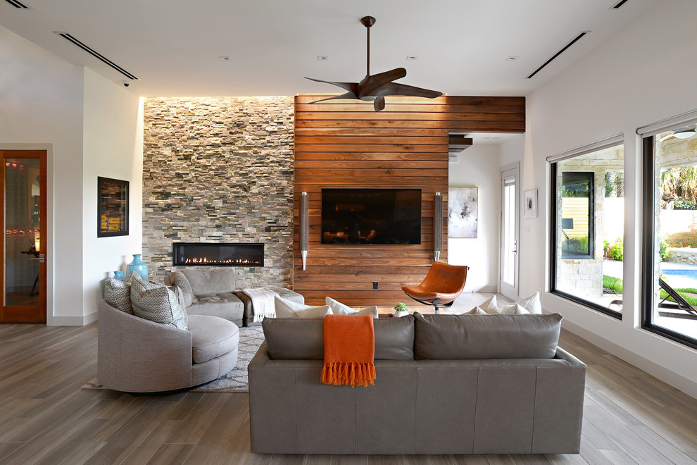 ダラスにある中くらいなコンテンポラリースタイルのおしゃれなLDK (白い壁、無垢フローリング、石材の暖炉まわり、横長型暖炉、壁掛け型テレビ、茶色い床) の写真