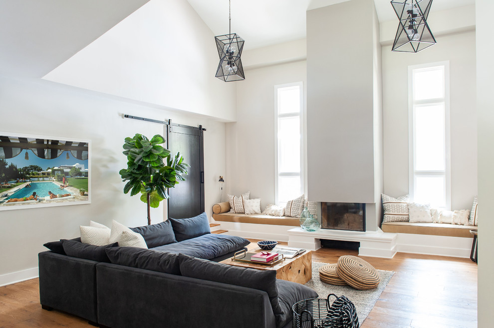 This is an example of a contemporary living room in Nashville with white walls, medium hardwood flooring, a standard fireplace and brown floors.