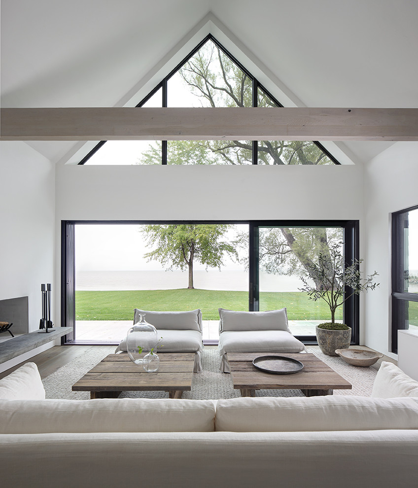 Cette image montre un salon minimaliste ouvert avec un mur blanc, parquet clair, une cheminée standard et un manteau de cheminée en plâtre.