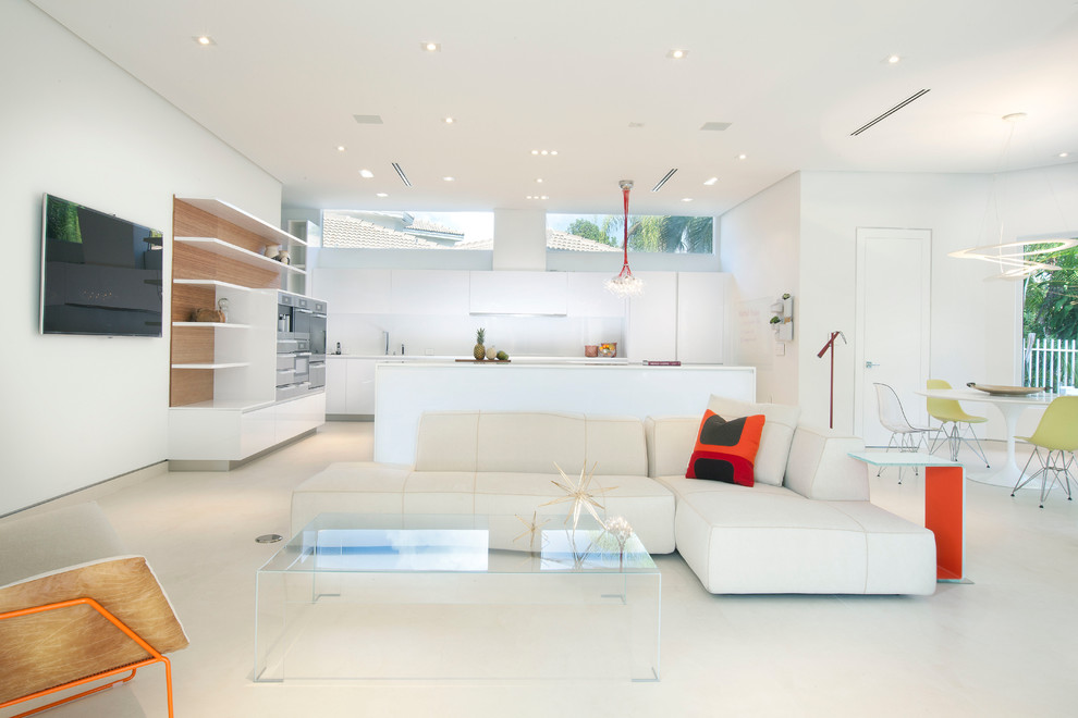 На фото: открытая гостиная комната в стиле модернизм с белыми стенами, телевизором на стене и белым полом с