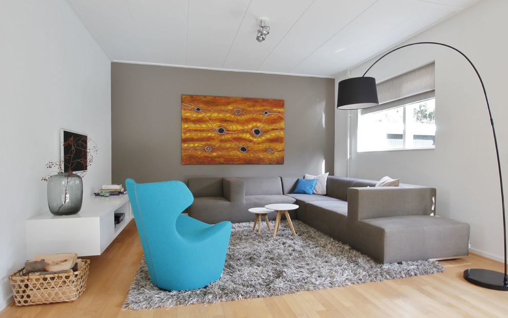 Bild på ett mellanstort funkis vardagsrum, med grå väggar, ljust trägolv och en väggmonterad TV