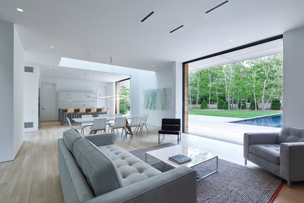 Foto di un soggiorno minimalista aperto con pareti bianche, parquet chiaro e pavimento beige