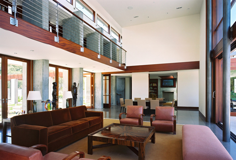 На фото: огромная открытая гостиная комната в стиле модернизм с белыми стенами и коричневым диваном