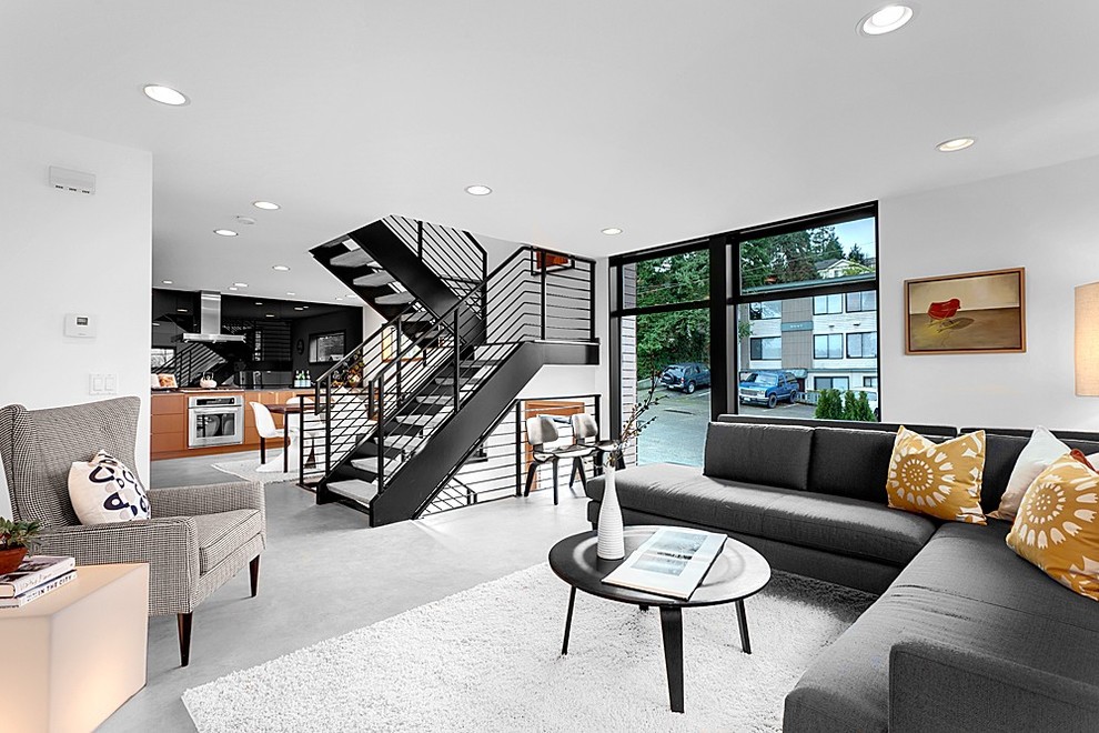 Cette image montre un salon minimaliste avec sol en béton ciré et un escalier.