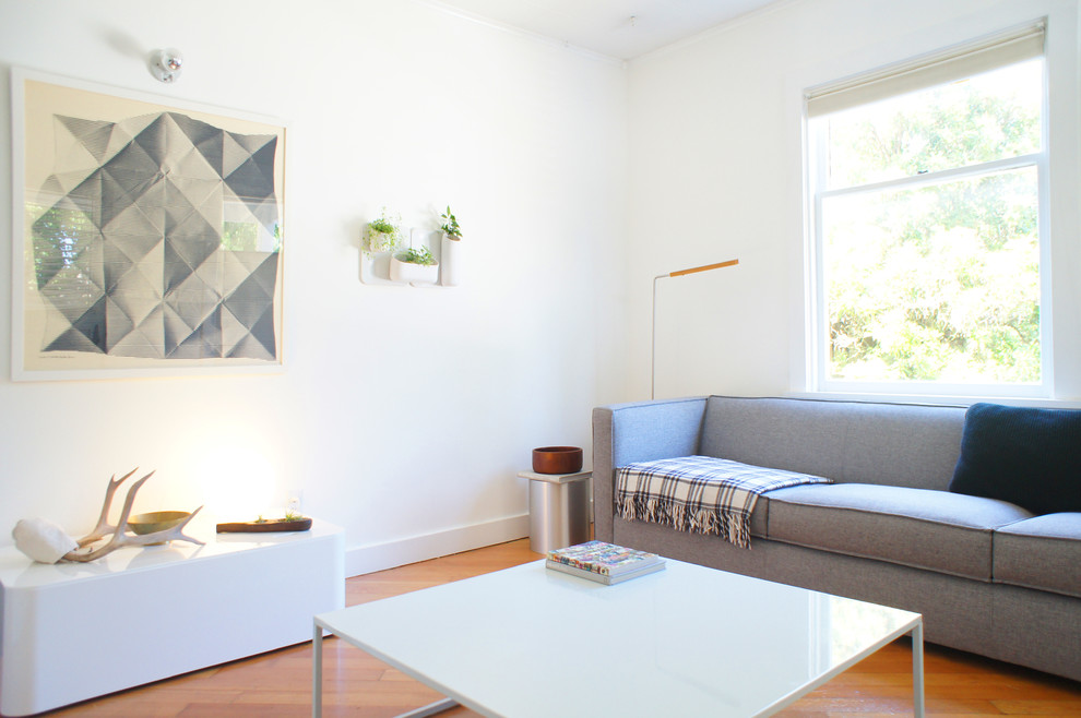 Example of a small minimalist open concept medium tone wood floor living room design in Seattle with white walls, no fireplace and no tv