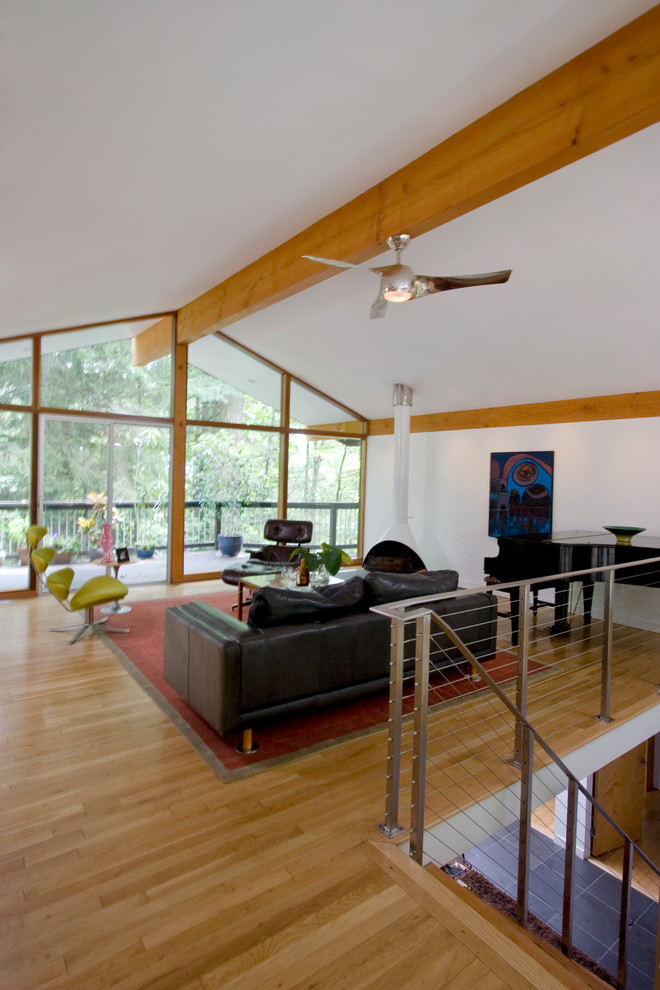 Immagine di un soggiorno moderno di medie dimensioni e stile loft con angolo bar, pareti bianche, parquet chiaro, camino sospeso e pavimento marrone