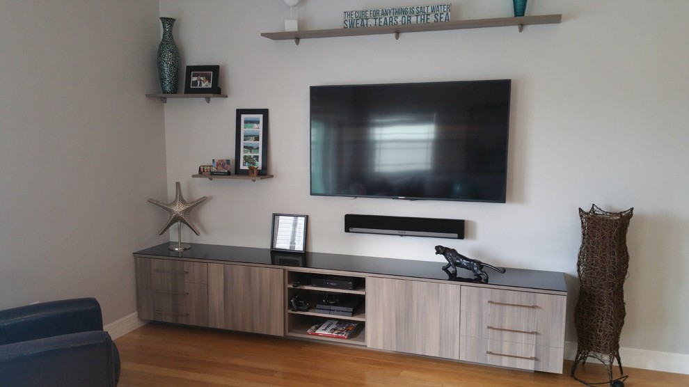 Foto di un soggiorno minimal di medie dimensioni e stile loft con pareti grigie, parquet chiaro e TV a parete