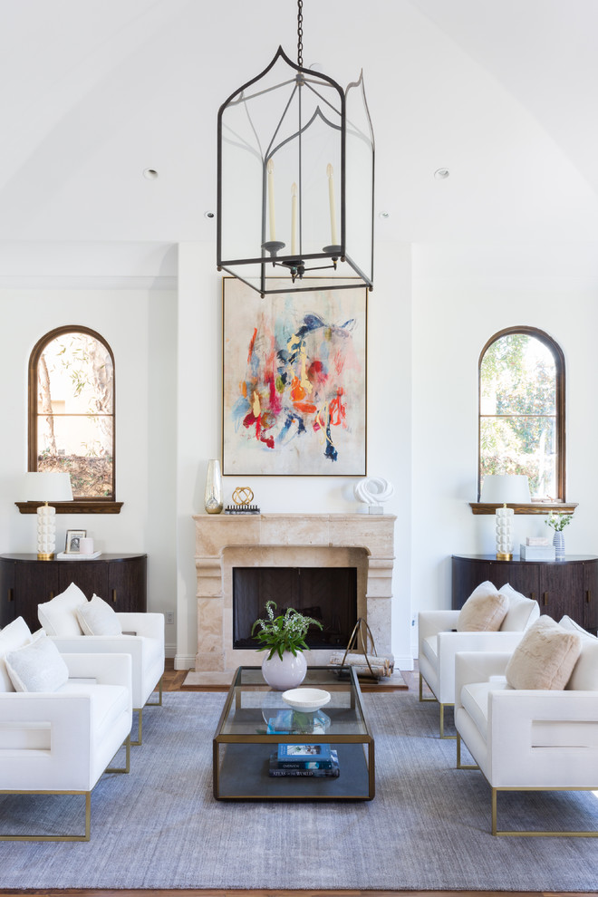 Example of a large tuscan formal and open concept medium tone wood floor and brown floor living room design in Los Angeles with white walls, a standard fireplace, a concrete fireplace and no tv