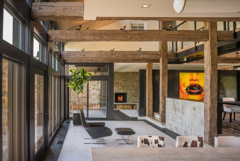 Идея дизайна: большая двухуровневая гостиная комната в современном стиле с домашним баром, черными стенами, стандартным камином, фасадом камина из камня и черным полом