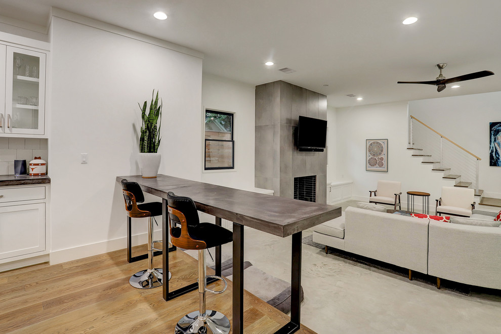 Стильный дизайн: большая открытая гостиная комната в стиле модернизм с белыми стенами, стандартным камином, телевизором на стене, паркетным полом среднего тона, фасадом камина из бетона и коричневым полом - последний тренд