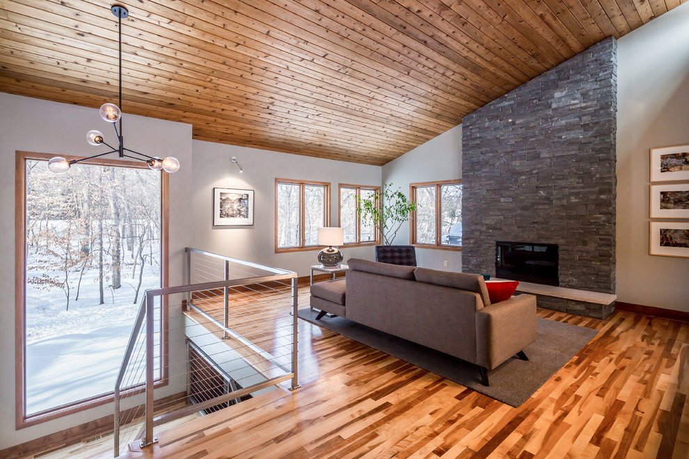 Offenes Modernes Wohnzimmer mit hellem Holzboden, Kamin und Kaminumrandung aus Stein in Minneapolis