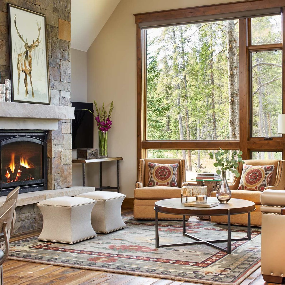 Rustic living room in Denver with beige walls, medium hardwood flooring, a standard fireplace, a stone fireplace surround and a wall mounted tv.