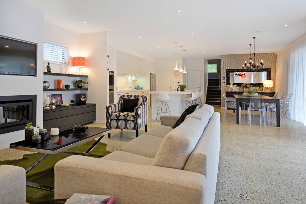 This is an example of a large contemporary open plan living room in Auckland with white walls, concrete flooring, a ribbon fireplace, a plastered fireplace surround and a wall mounted tv.