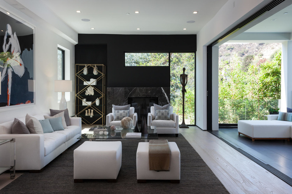Großes, Repräsentatives, Fernseherloses, Offenes Modernes Wohnzimmer mit schwarzer Wandfarbe, hellem Holzboden, Kamin und Kaminumrandung aus Stein in Los Angeles