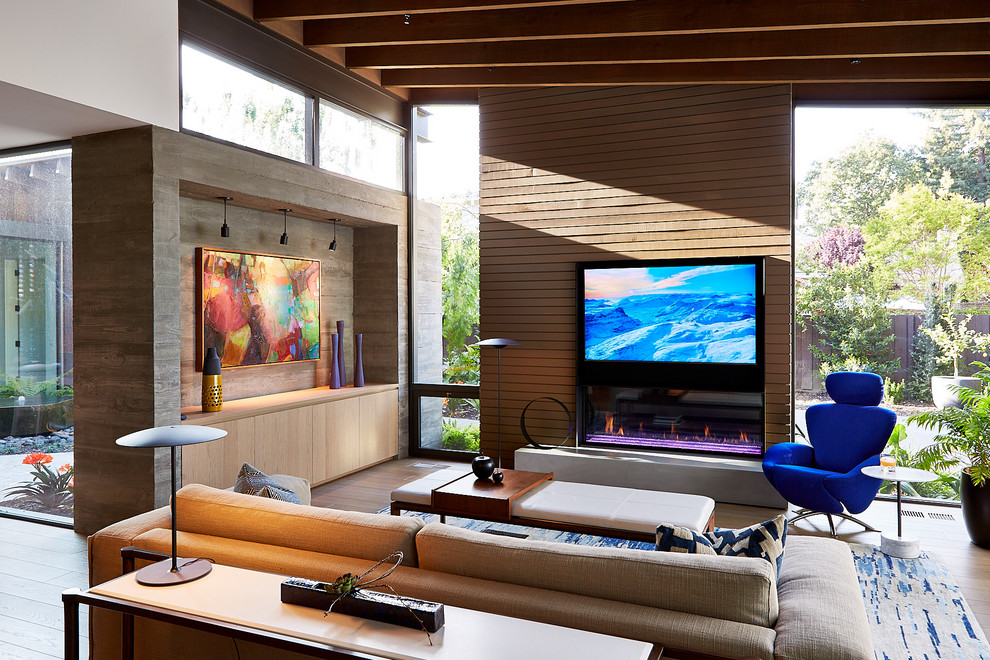 Imagen de salón abierto actual con marco de chimenea de metal, pared multimedia, suelo de madera en tonos medios, chimenea lineal y suelo marrón