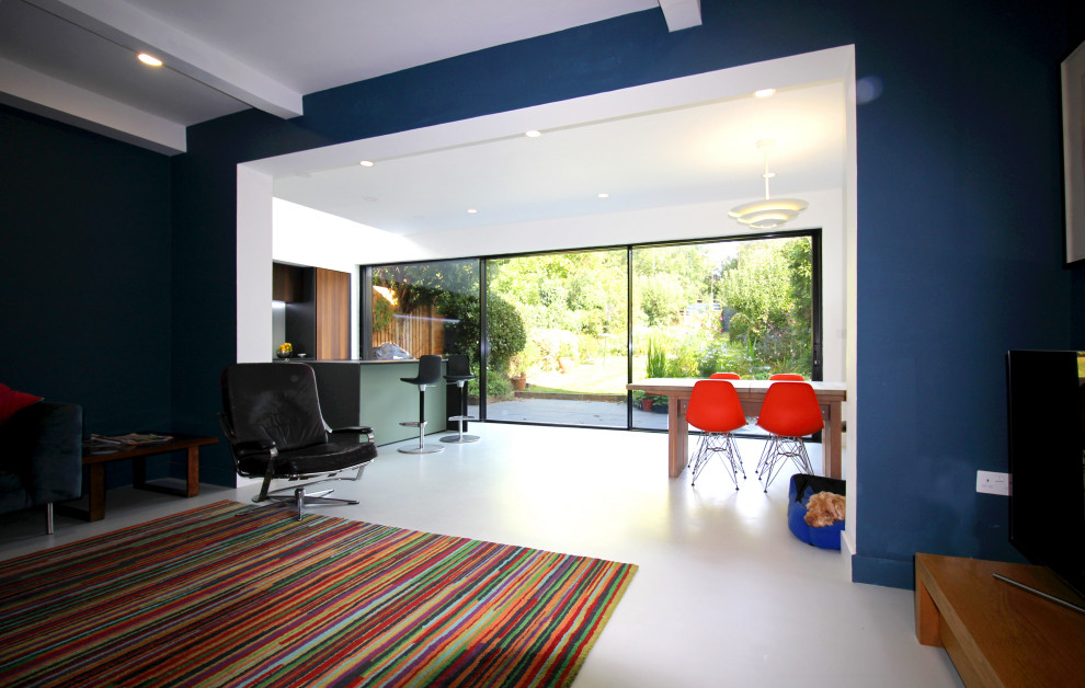 Cette image montre un salon minimaliste de taille moyenne et ouvert avec un sol gris, un mur bleu et un téléviseur indépendant.