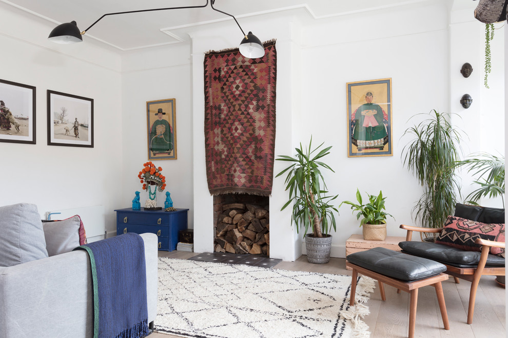 This is an example of a large eclectic open plan living room in Edinburgh with white walls, light hardwood flooring, a standard fireplace, a plastered fireplace surround and brown floors.