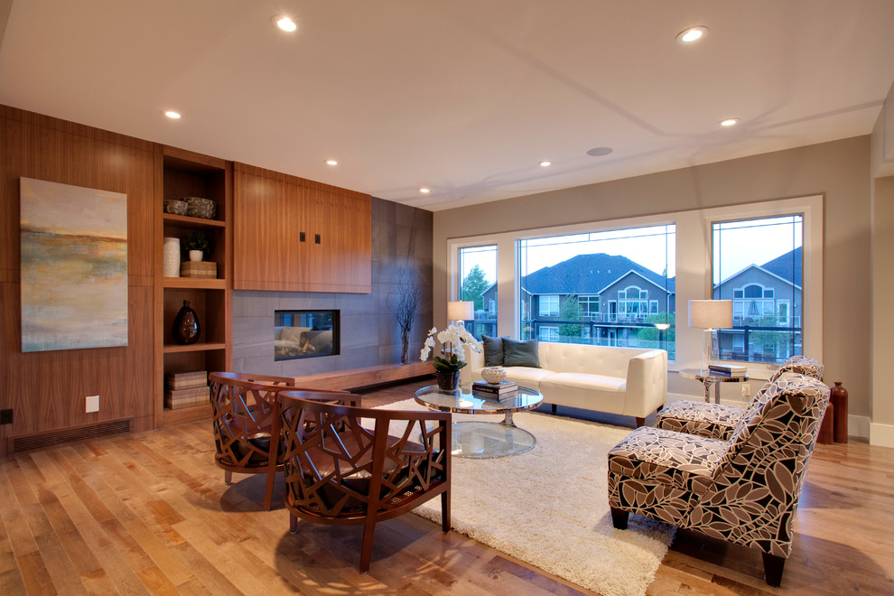 Modernes Wohnzimmer mit grauer Wandfarbe, TV-Wand, braunem Holzboden, Kamin und gefliester Kaminumrandung in Calgary