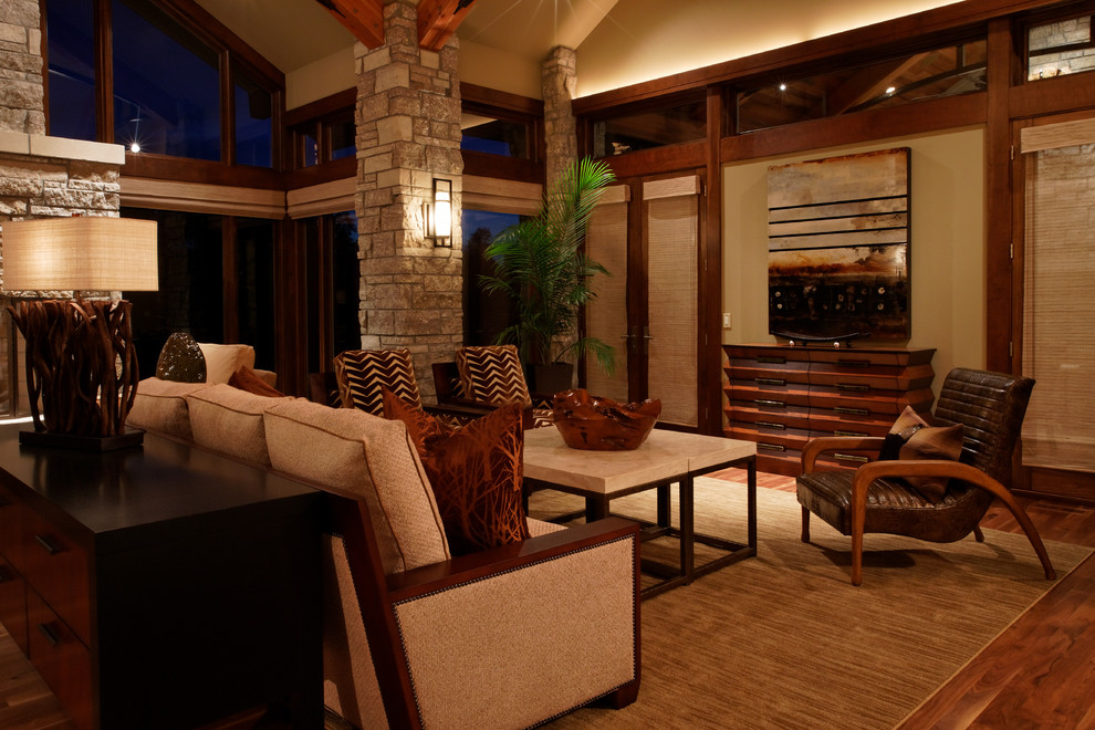 Immagine di un ampio soggiorno design aperto con pareti beige, pavimento in legno massello medio, camino classico e cornice del camino in pietra