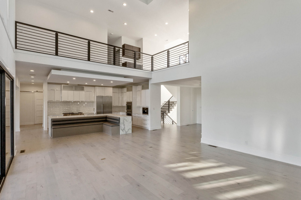 Ejemplo de salón abierto minimalista grande con paredes blancas, suelo de madera clara, chimenea lineal, marco de chimenea de baldosas y/o azulejos y suelo gris