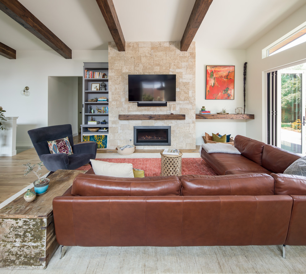 Design ideas for a medium sized contemporary open plan living room in Denver with white walls, light hardwood flooring, a standard fireplace, a stone fireplace surround, a wall mounted tv, brown floors and exposed beams.