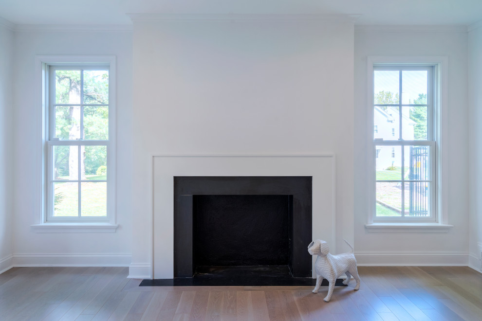 Cette photo montre un salon moderne de taille moyenne et fermé avec un mur blanc, parquet clair, une cheminée standard, un manteau de cheminée en bois et un sol noir.