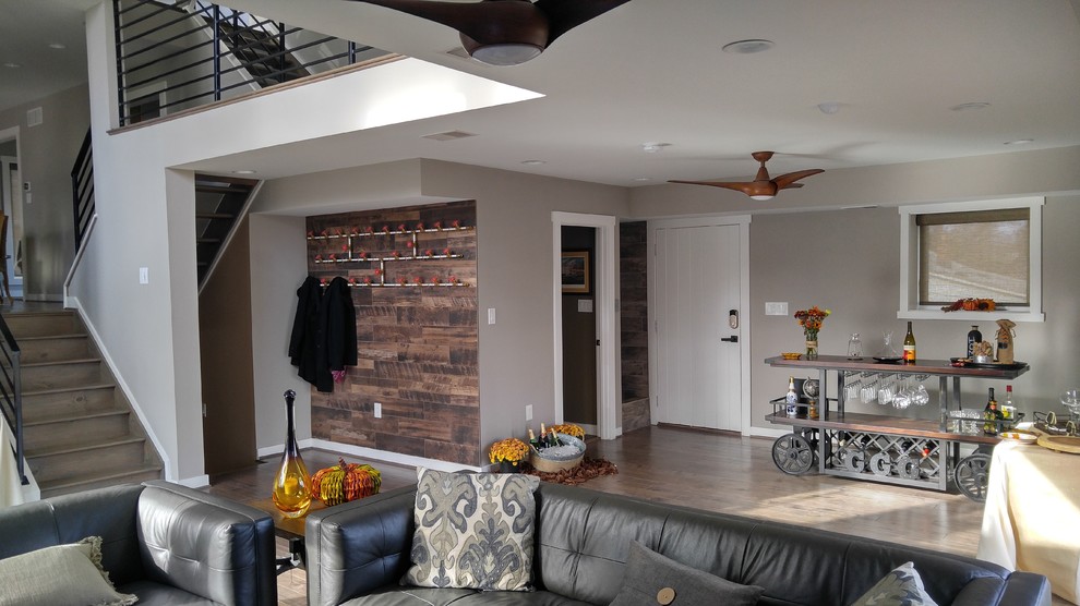 Diseño de salón con barra de bar abierto industrial grande con paredes grises, suelo de madera en tonos medios y suelo marrón