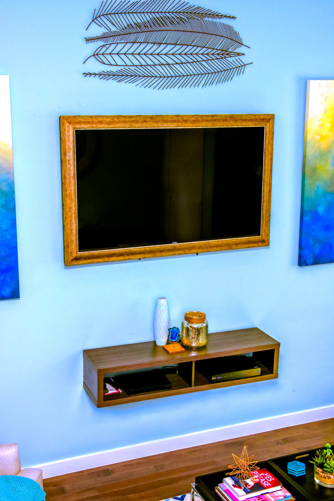 Réalisation d'un petit salon minimaliste ouvert avec un mur bleu, un sol en bois brun, un téléviseur fixé au mur et un sol gris.
