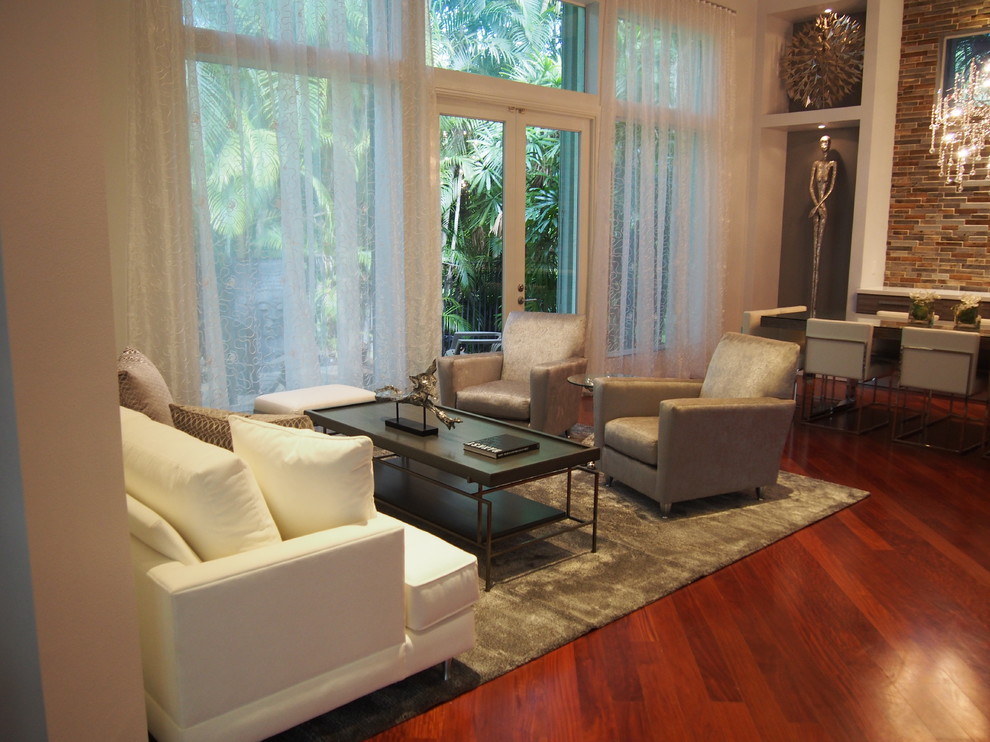 Fernseherloses, Offenes Modernes Wohnzimmer ohne Kamin mit grauer Wandfarbe und braunem Holzboden in Miami