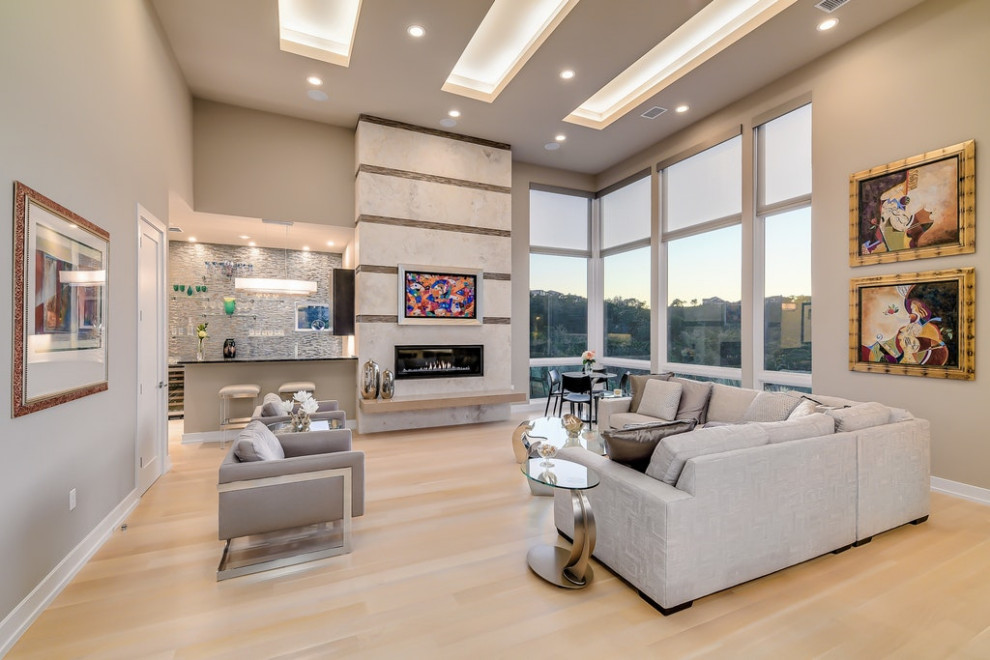 Offenes Modernes Wohnzimmer mit grauer Wandfarbe, hellem Holzboden, Gaskamin, beigem Boden und eingelassener Decke in Austin
