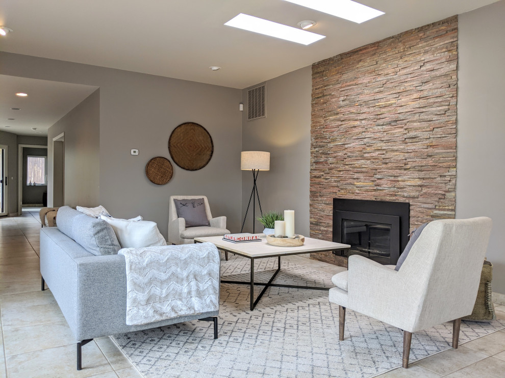 Стильный дизайн: открытая гостиная комната среднего размера в стиле модернизм с серыми стенами, полом из травертина, стандартным камином, фасадом камина из каменной кладки и бежевым полом без телевизора - последний тренд