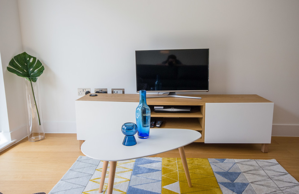 Imagen de salón abierto nórdico pequeño con paredes blancas, suelo laminado, televisor independiente y suelo marrón