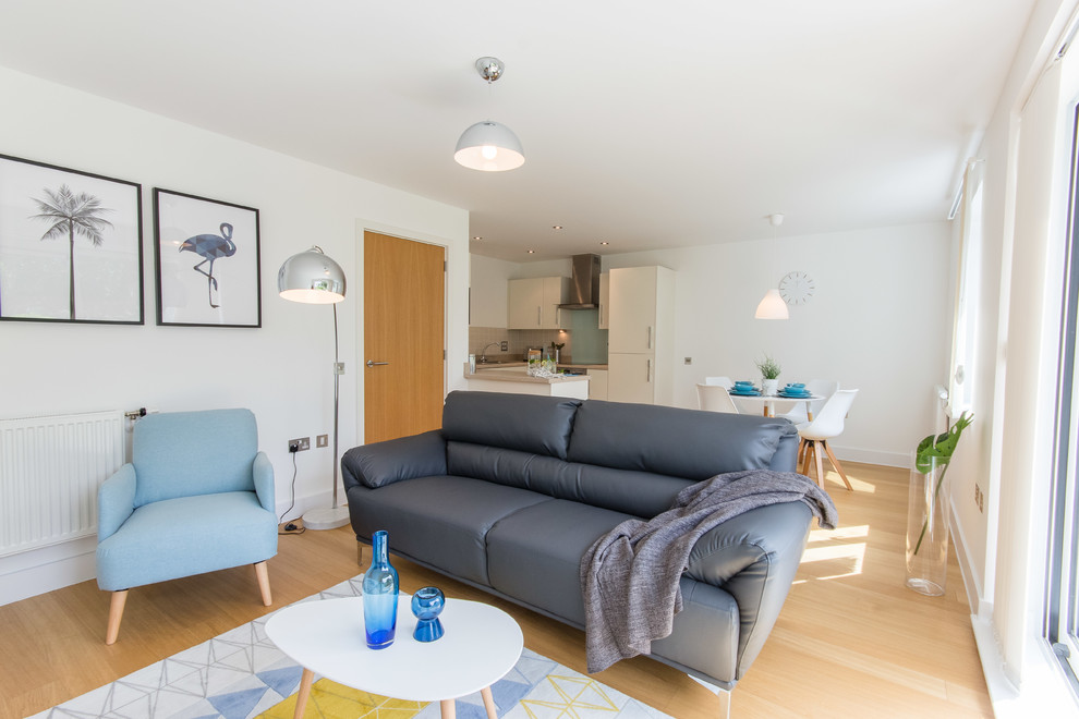 Modelo de salón abierto nórdico pequeño con paredes blancas, suelo laminado, televisor independiente y suelo marrón