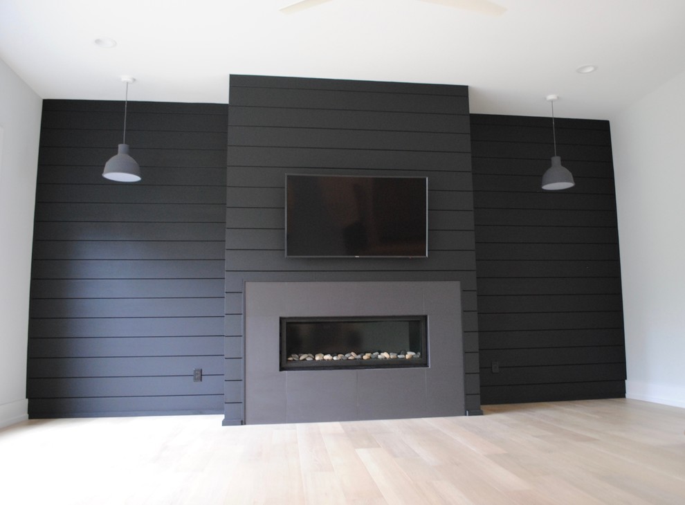 ローリーにある高級な中くらいな北欧スタイルのおしゃれなLDK (黒い壁、淡色無垢フローリング、横長型暖炉、タイルの暖炉まわり、壁掛け型テレビ) の写真