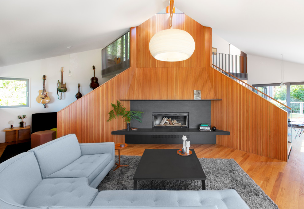 Idéer för ett mellanstort modernt loftrum, med vita väggar, ljust trägolv och en öppen vedspis