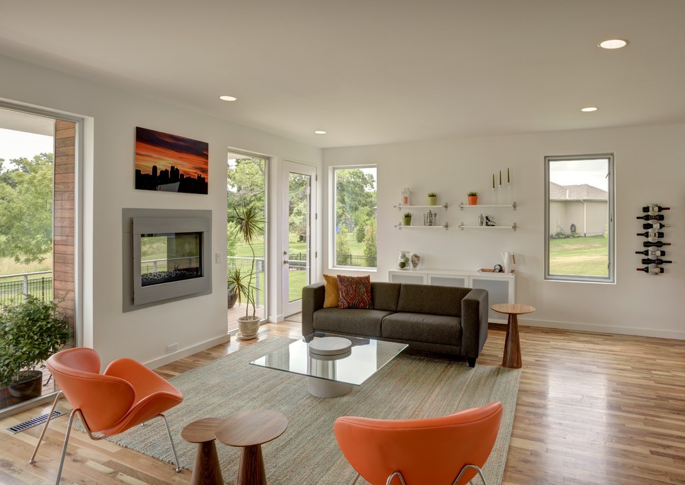 Offenes Modernes Wohnzimmer mit weißer Wandfarbe, Tunnelkamin und braunem Holzboden in Kansas City