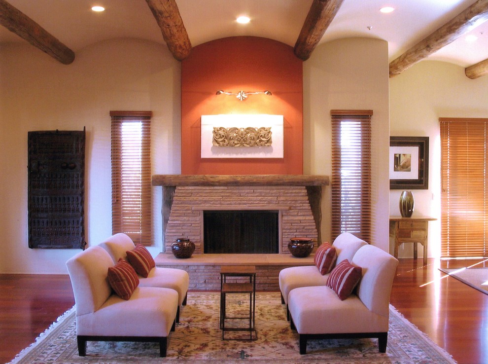 Großes, Offenes Modernes Wohnzimmer mit oranger Wandfarbe, braunem Holzboden und Kaminumrandung aus Stein in Orange County