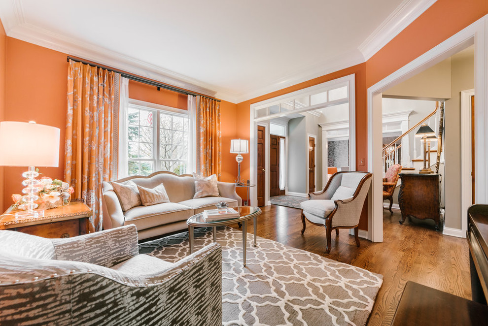 Foto di un soggiorno chic di medie dimensioni e aperto con sala formale, pareti arancioni, pavimento in legno massello medio, nessuna TV e pavimento marrone
