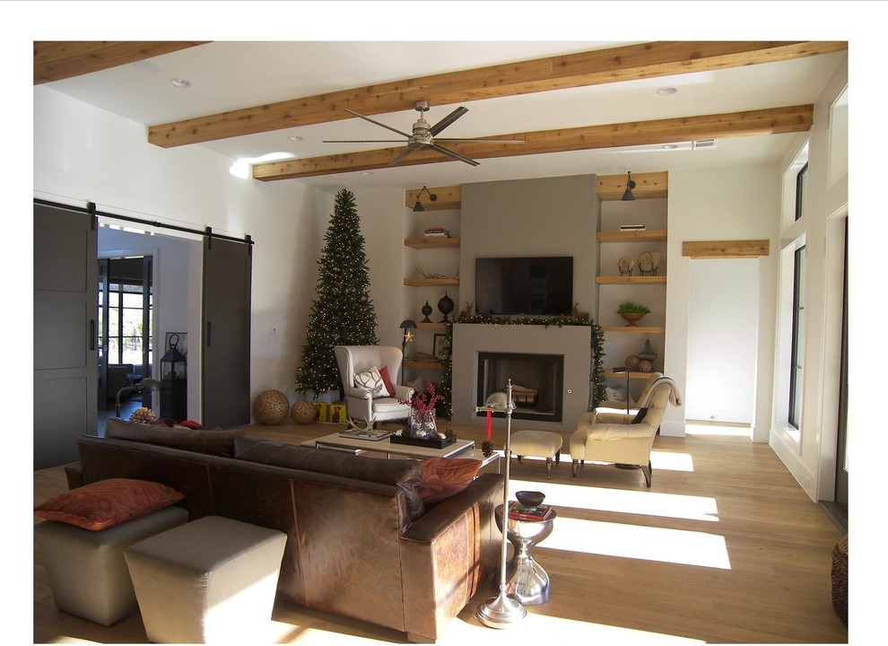 Example of an urban open concept light wood floor living room design in Dallas with white walls, a standard fireplace, a concrete fireplace and a wall-mounted tv