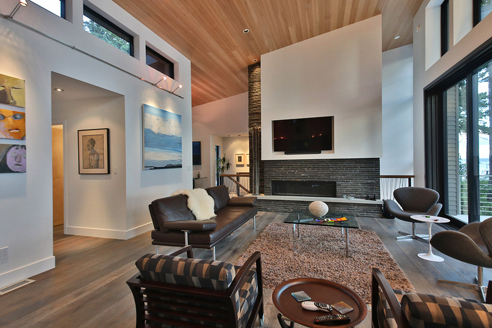 Großes, Offenes Modernes Wohnzimmer mit weißer Wandfarbe, braunem Holzboden, Gaskamin, Kaminumrandung aus Stein, TV-Wand und braunem Boden in Seattle