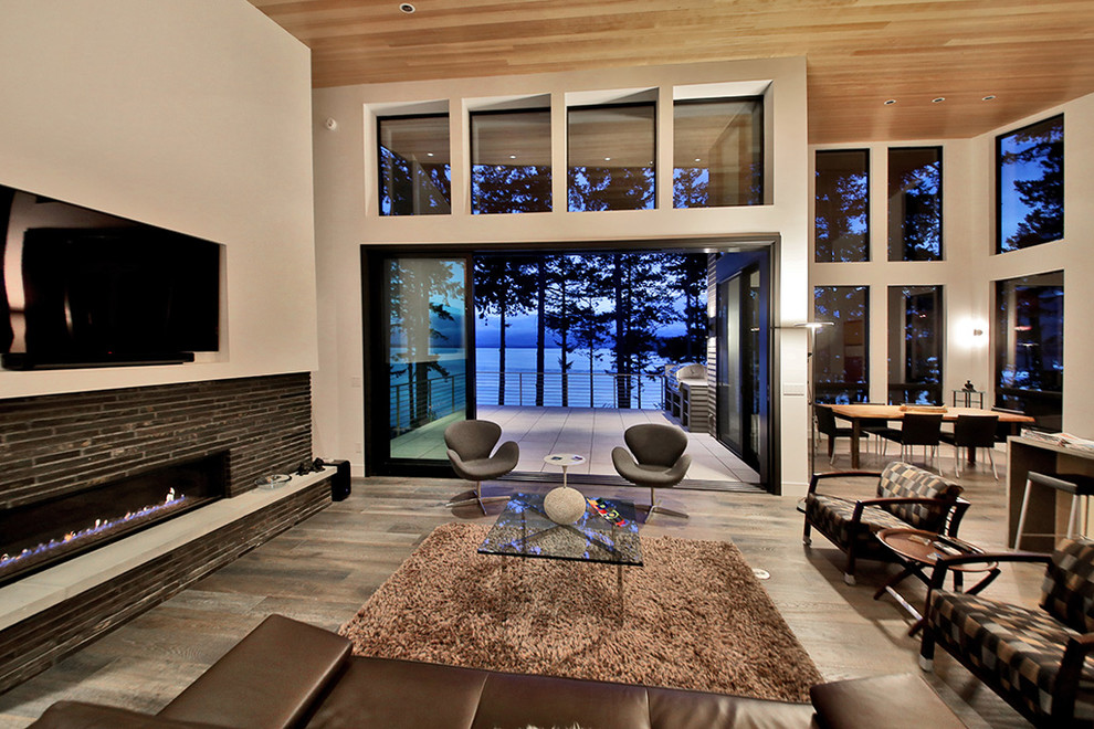 Источник вдохновения для домашнего уюта: большая открытая гостиная комната в стиле модернизм с белыми стенами, паркетным полом среднего тона, горизонтальным камином, фасадом камина из камня, телевизором на стене и коричневым полом